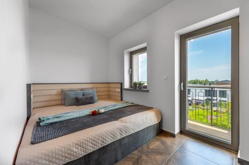 a bedroom with a bed and a large window at LASKARA Garden Apartment by Prague Forest in Nové Jirny