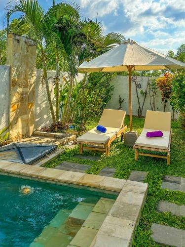 two chairs and an umbrella next to a swimming pool at Nate's Villa - 2 Bedroom Villa Private Pool near Lovina Bali in Banjar