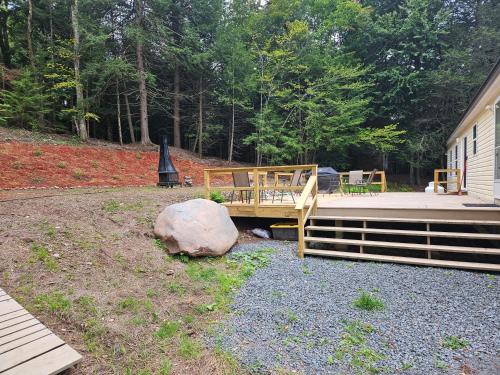 a wooden deck with a bench and a rock at Tranquil renovated house in woods - great for families year around in Tannersville