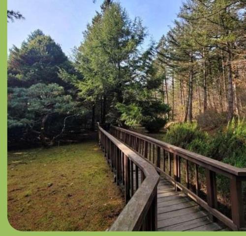 un puente de madera sobre un campo con árboles en A Four Leaf Clover House, en Namyangju