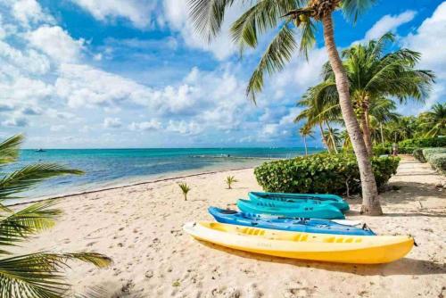 a yellow canoe on a beach with palm trees and the ocean at Conch Club Cottage in Head of Bay