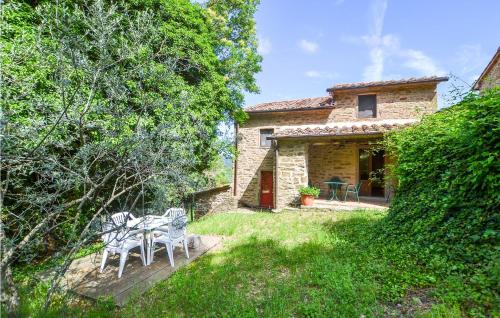 a stone house with a table and chairs in a yard at Cozy Home In Castiglion Fiorentino in Castiglion Fiorentino