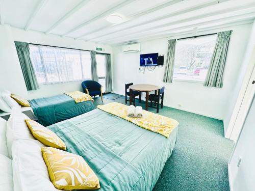 1 dormitorio con 2 camas y mesa. en Gothic Heights Motel, en Christchurch