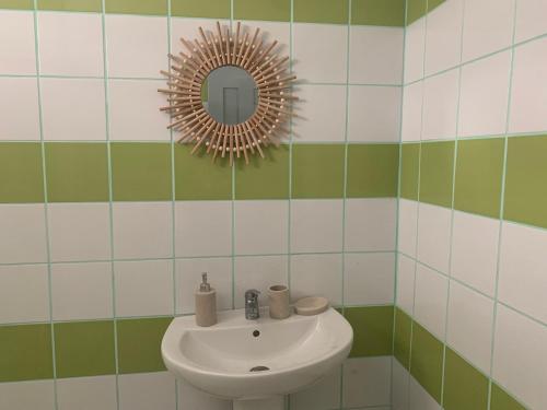 W łazience znajduje się umywalka i lustro. w obiekcie Les Roses Porcelaines w mieście Sainte-Rose