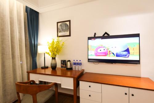 a room with a desk and a tv on a wall at Four Seasons Are Picturesque Guesthouse in Zhangjiajie