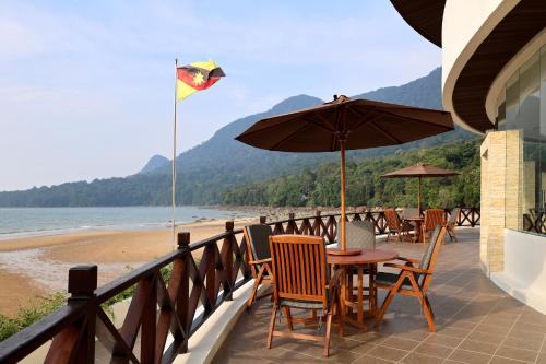 a table with chairs and an umbrella on the beach at Damai Lagoon Resort in Santubong