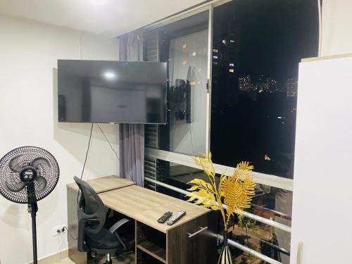 a room with a desk and a tv and a window at Apartamento acogedor en el poblado Medellín in Medellín