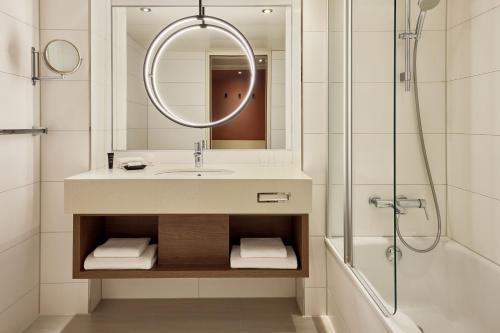 a bathroom with a sink and a shower and a mirror at Sheraton Frankfurt Airport Hotel & Conference Center in Frankfurt/Main