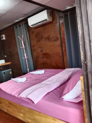 ein großes Bett in einem Zimmer mit einer rosa Decke in der Unterkunft บ้านทุ่งโฮมสเตย์ in Ban Chai Khlong