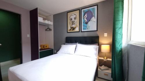 a bedroom with a bed and two pictures on the wall at Departamento Completo Frente al Aeropuerto in Mexico City
