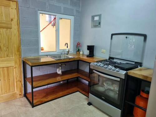 a kitchen with a stove and a sink at Hostal Camila’s in Tamanique