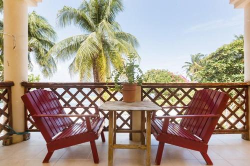 two chairs and a table on a balcony with a palm tree at Marysol D8 beachfront next to nomads in Isla Mujeres
