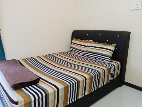 una cama con una manta a rayas encima en NQ Jelawat HOMESTAY en Bachok