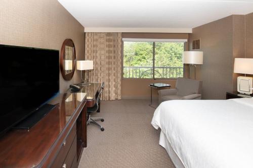 a hotel room with a bed and a flat screen tv at Sheraton Hartford South in Rocky Hill