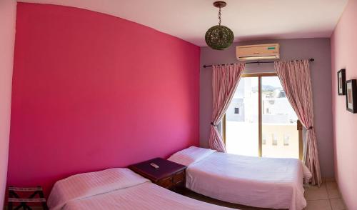 two beds in a room with a pink wall at Garimar Condominios en San Carlos in San Carlos
