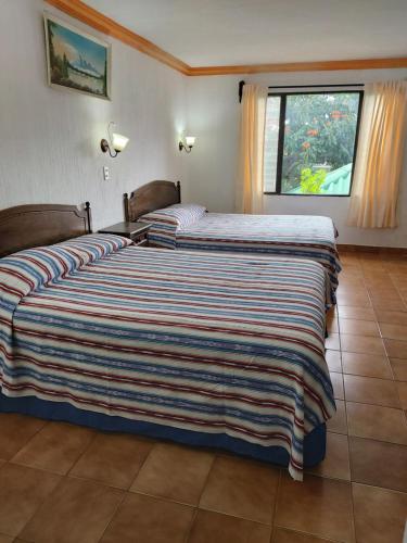 a bedroom with two beds and a large window at Perla Maya Hotel in Panajachel