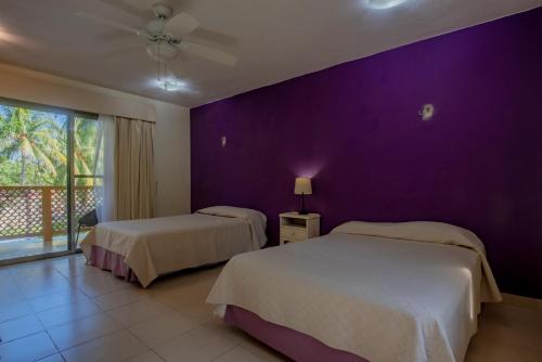 a bedroom with two beds and a purple wall at Marysol d10 private beach next to nomads in Isla Mujeres