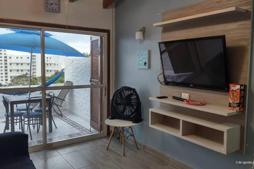 a living room with a television and a balcony at SUITE DENTRO DEL CLUB CASA BLANCA EN SAME in Volcán Chimborazo