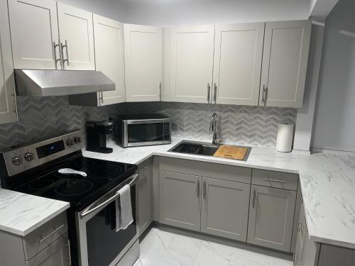 a kitchen with white cabinets and a stove top oven at Casa LACK - Tranquila Suites 3 in Ottawa