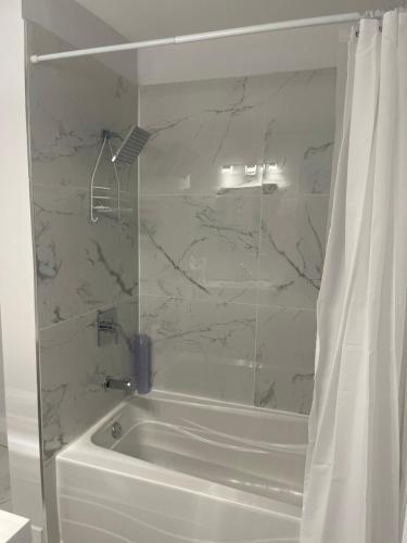 a bathroom with a white tub with a shower curtain at Casa LACK - Tranquila Suites 3 in Ottawa