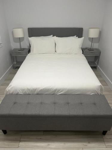 uma cama grande com lençóis brancos e duas lâmpadas em Casa LACK - Tranquila Suites 3 em Ottawa