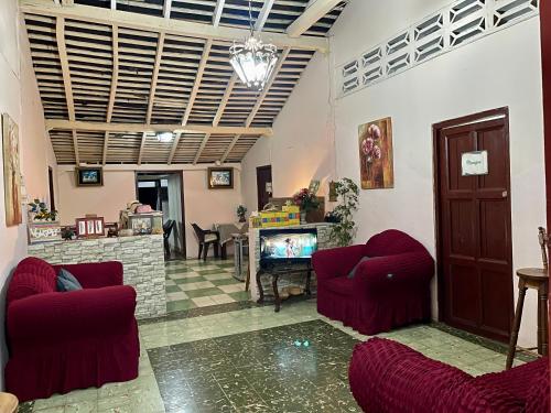 a living room with two red chairs and a fireplace at Hostal Voyager La Villa de Los Santos, Panama in Los Santos