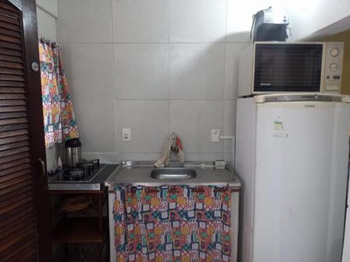 una pequeña cocina con fregadero y nevera. en 1 Casa piso superior e 1 Kitnet Térrea, individuais, o estacionamento área comum en Bertioga