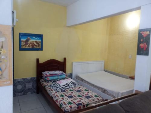 a bedroom with two beds in a room at 1 Casa piso superior e 1 Kitnet Térrea, individuais, o estacionamento área comum in Bertioga