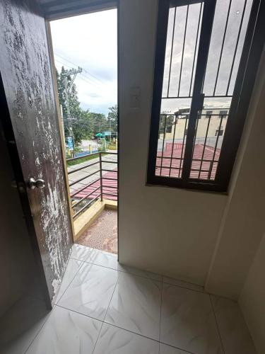 uma porta aberta com uma janela num quarto em Aien's Apartelle em Mati