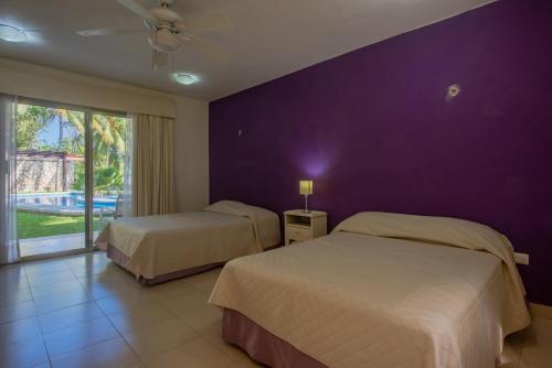 una camera da letto con due letti e una parete viola di Marysol d11 private beach next to nomads a Isla Mujeres