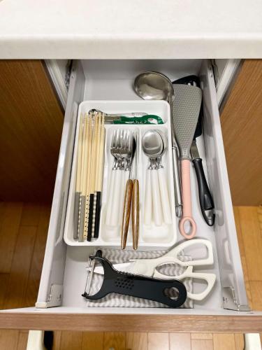 a drawer filled with kitchen utensils in a cabinet at Thanyaporn Hotel in Takayama