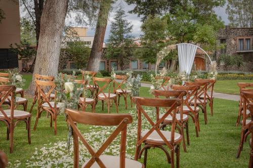 a row of chairs sitting in the grass with a table at Holiday Inn Tlaxcala by IHG in Tlaxcala de Xicohténcatl