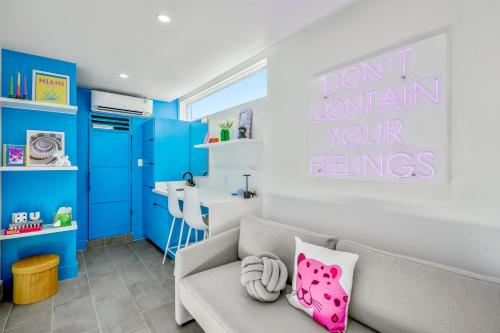 Una sala de estar con paredes azules y un sofá con una almohada rosa. en Blueberry Container @ EADO Juice Box, en Houston