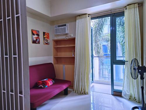 a living room with a red couch and a window at 1BR at TWO PALMTREE VILLAS Across Manila airport terminal 3 in Manila