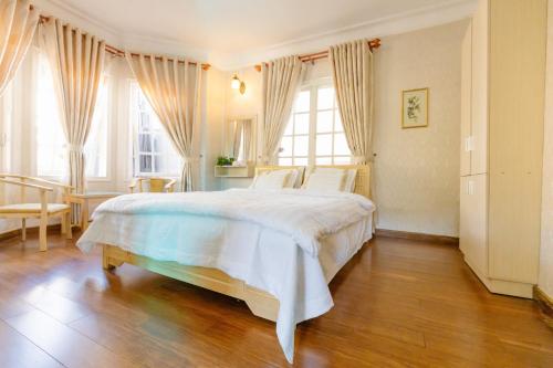 a bedroom with a large white bed and windows at BACH TÙNG Garden Village in Xuan An