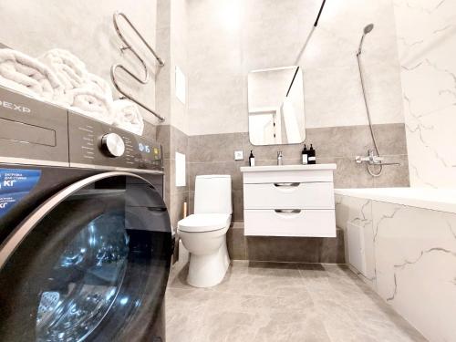 ein Badezimmer mit einer Waschmaschine, einem WC und einem Waschbecken in der Unterkunft Уютные апартаменты ЖК Galamat towers in Taldykolʼ