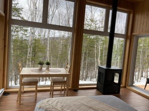 a bedroom with a table and a fireplace in front of a window at Tanières MicroChalets Charlevoix in Baie-Saint-Paul
