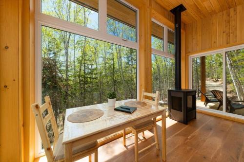 une salle à manger avec une table et une grande fenêtre dans l'établissement Tanières MicroChalets Charlevoix, à Baie-Saint-Paul
