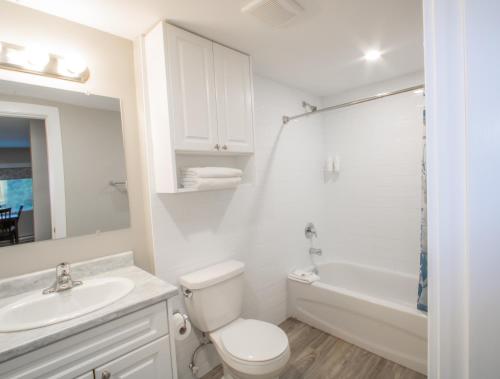 a white bathroom with a toilet and a sink and a tub at Scott's Inn & Suites in Kamloops