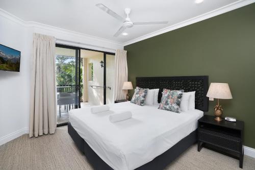 a bedroom with a large white bed and a balcony at Club Wyndham Cairns in Cairns