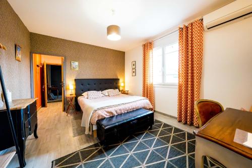 a bedroom with a bed and a desk and a window at La Maison Jaffran, suite en ville in Privas