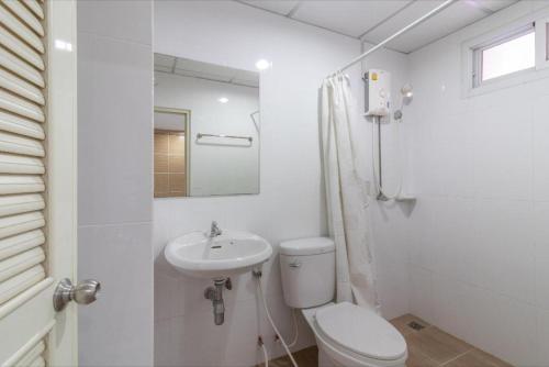 a white bathroom with a toilet and a sink at Siam Privi Hotel in Bangkok