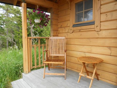 a wooden chair and a stool on the porch of a cabin at Tornvillan in Hammarland