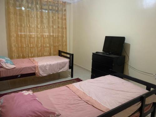 a bedroom with two beds and a tv on a dresser at Apartement Boulevard Mohammed Derfoufi Oujda in Oujda