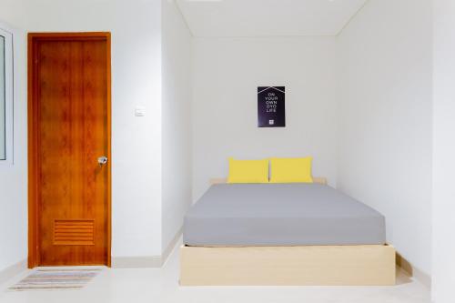 1 dormitorio con 1 cama y puerta de madera en OYO Life 1830 Mandala Residence, en Yakarta