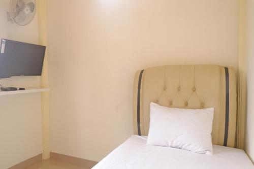 a bed with a white pillow and a television at OYO Life 92632 Kost Pondok Kito in Jambi