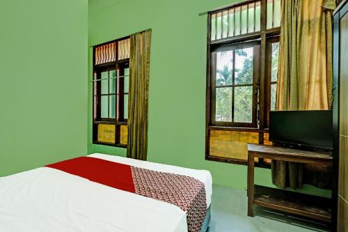 1 dormitorio con 1 cama, TV y ventanas en OYO Life 91682 Homestay Sriti en Kalibanteng-kidul