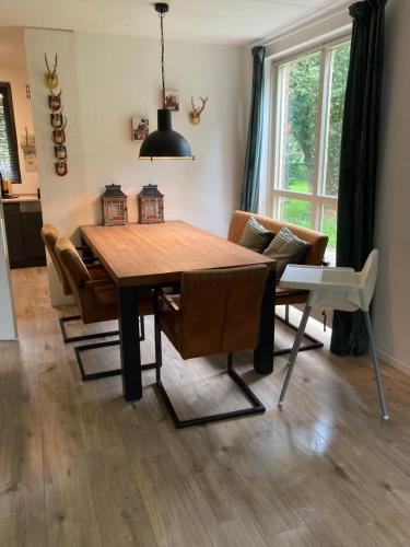 a dining room with a wooden table and chairs at Forest Vacation Home -fenced garden- in Ewijk