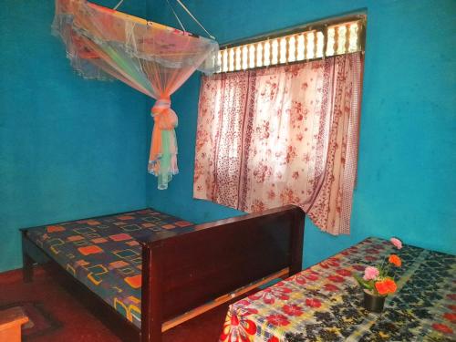 Cette chambre bleue comprend un lit et une fenêtre. dans l'établissement Simba Guest house, à Sigirîya
