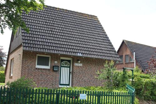 a brick house with a fence in front of it at Haus Dat lüttje Huus in Krummhörn